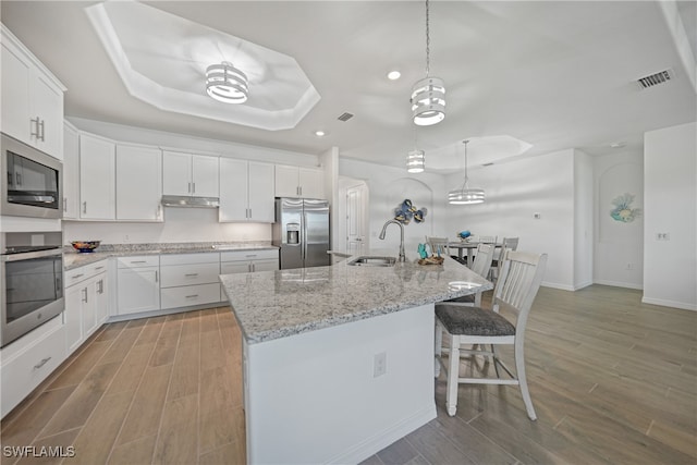 kitchen featuring white cabinetry, sink, light hardwood / wood-style floors, a kitchen island with sink, and appliances with stainless steel finishes