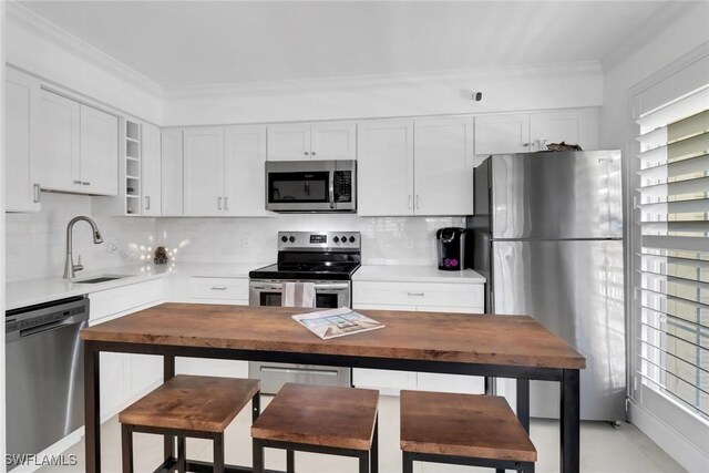 kitchen with wooden counters, appliances with stainless steel finishes, backsplash, sink, and white cabinetry