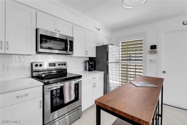 kitchen featuring decorative backsplash, appliances with stainless steel finishes, and white cabinetry