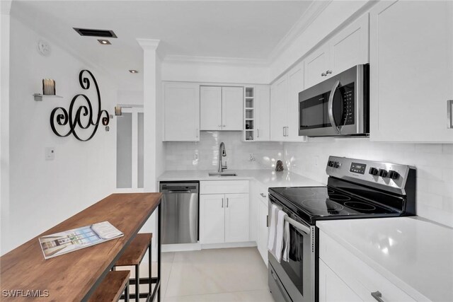 kitchen with sink, stainless steel appliances, backsplash, white cabinets, and ornamental molding