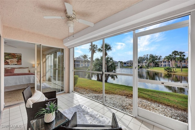 sunroom featuring a water view, ceiling fan, and a wealth of natural light