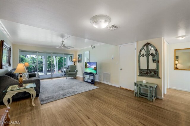 living room featuring ceiling fan, hardwood / wood-style floors, and crown molding