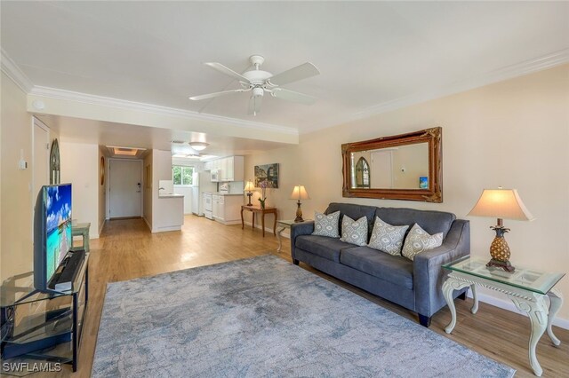 living room featuring crown molding, light hardwood / wood-style flooring, and ceiling fan