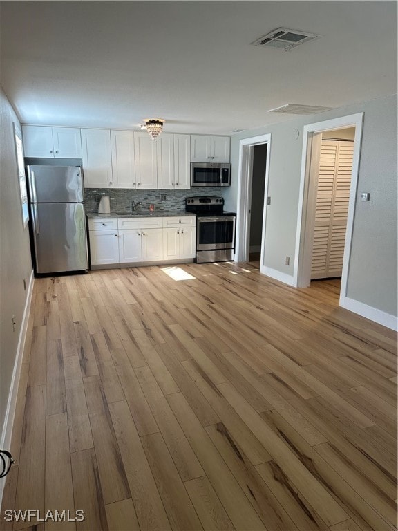 kitchen with visible vents, decorative backsplash, appliances with stainless steel finishes, white cabinetry, and light wood-type flooring