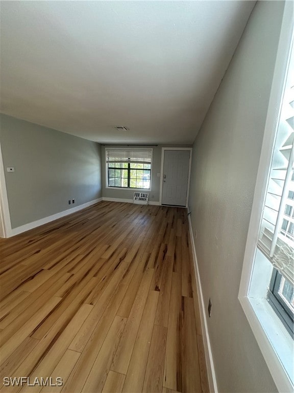 unfurnished living room featuring baseboards, visible vents, and light wood finished floors