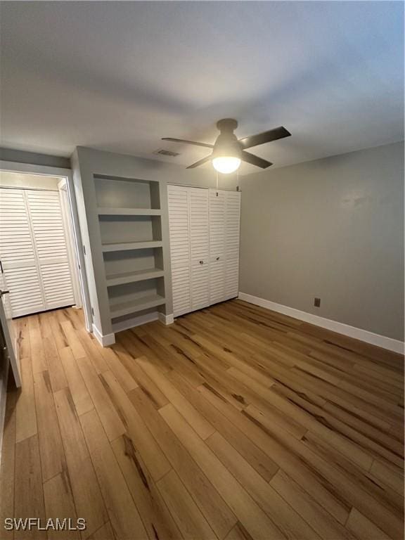 unfurnished bedroom with a ceiling fan, visible vents, baseboards, and wood finished floors