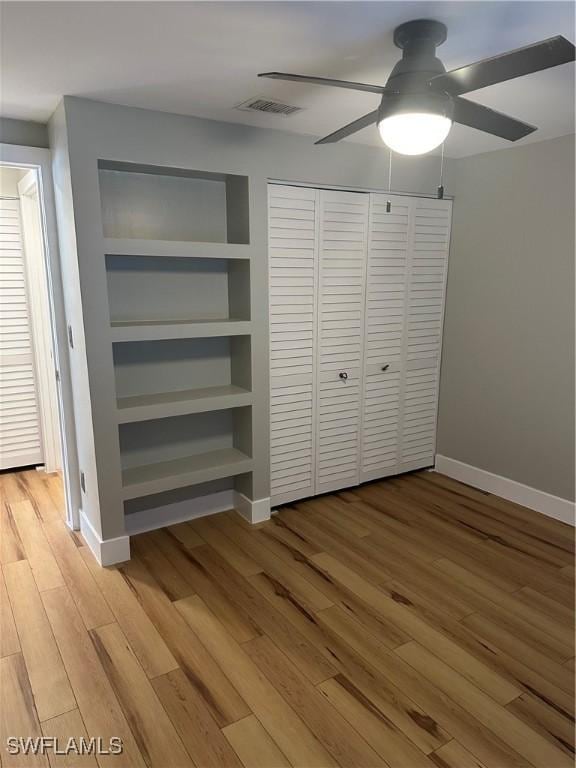 unfurnished bedroom featuring baseboards, visible vents, ceiling fan, light wood-style floors, and a closet