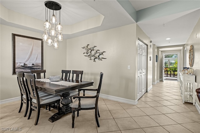 dining space with light tile patterned floors, a notable chandelier, a raised ceiling, and baseboards