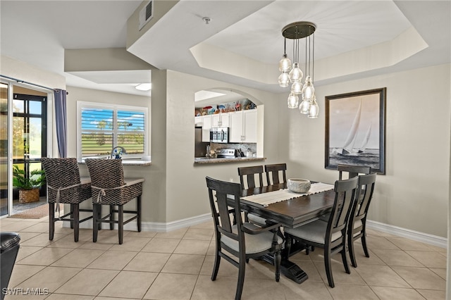 dining space featuring light tile patterned floors and a tray ceiling