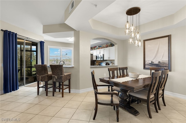 dining space with a raised ceiling, visible vents, baseboards, and light tile patterned floors