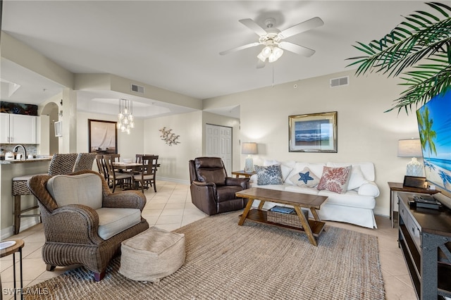 living room with sink, light tile patterned floors, and ceiling fan with notable chandelier