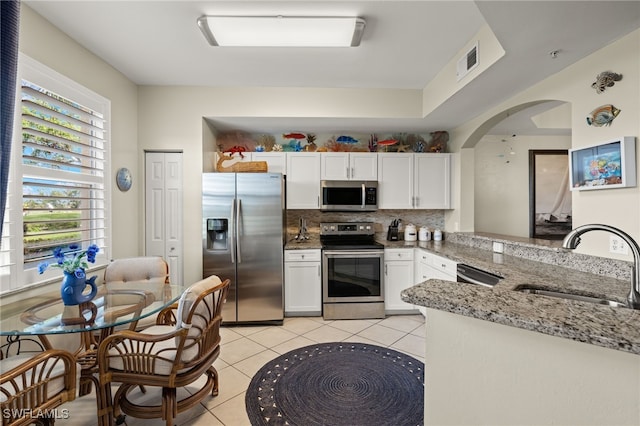 kitchen featuring sink, appliances with stainless steel finishes, tasteful backsplash, light stone counters, and white cabinetry