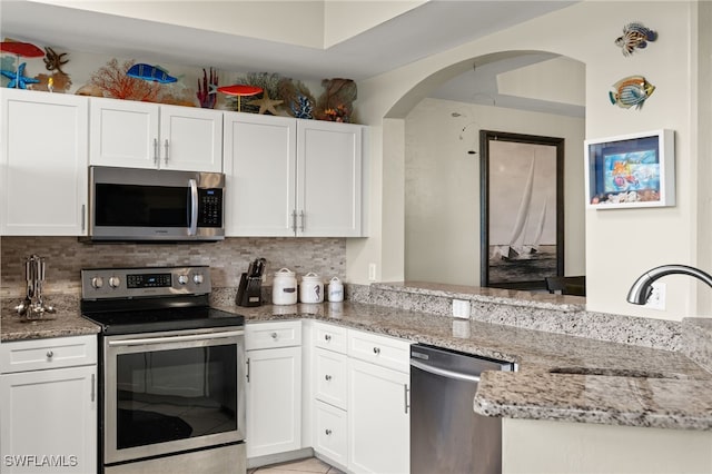 kitchen featuring white cabinets, tasteful backsplash, light stone counters, and stainless steel appliances