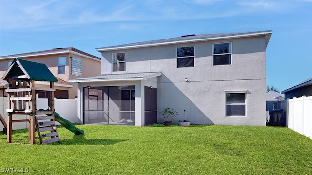 rear view of property featuring a sunroom, a playground, and a yard