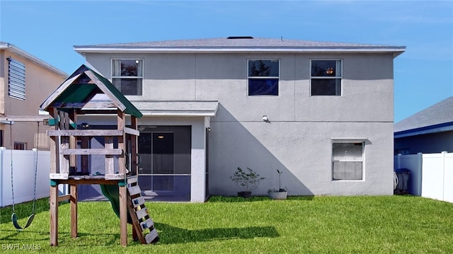 back of property featuring a lawn, a sunroom, and a playground