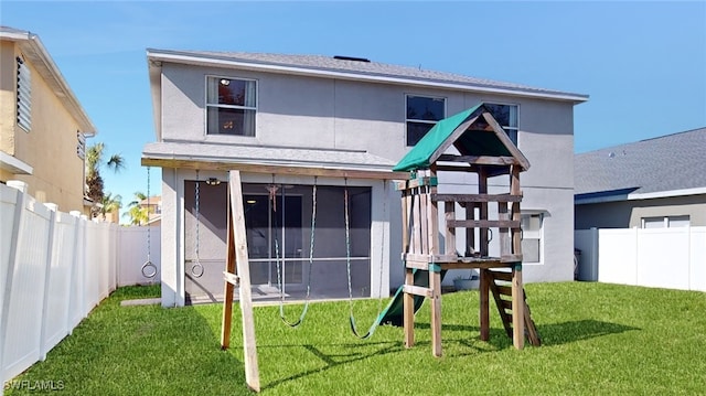 rear view of property featuring a yard, a playground, and a sunroom