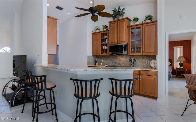 kitchen featuring a kitchen bar, kitchen peninsula, and high vaulted ceiling