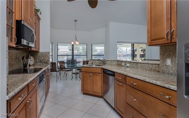 kitchen with pendant lighting, plenty of natural light, light stone countertops, and appliances with stainless steel finishes