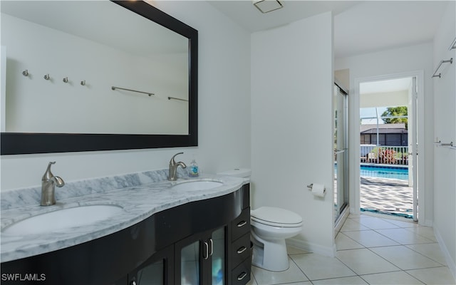 bathroom featuring toilet, vanity, tile patterned floors, and a shower with shower door