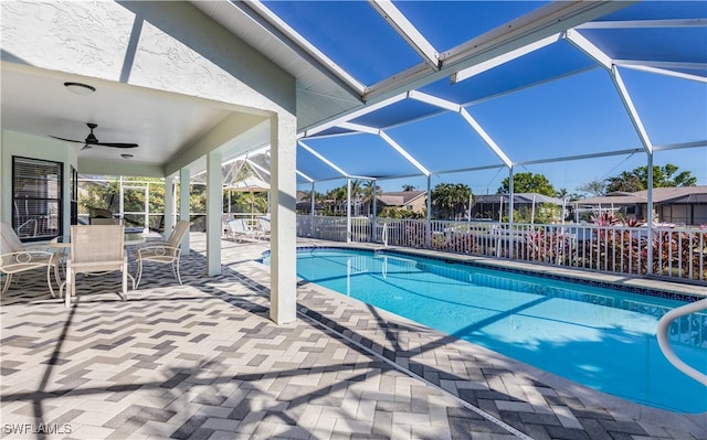 view of swimming pool featuring ceiling fan, a patio, and glass enclosure