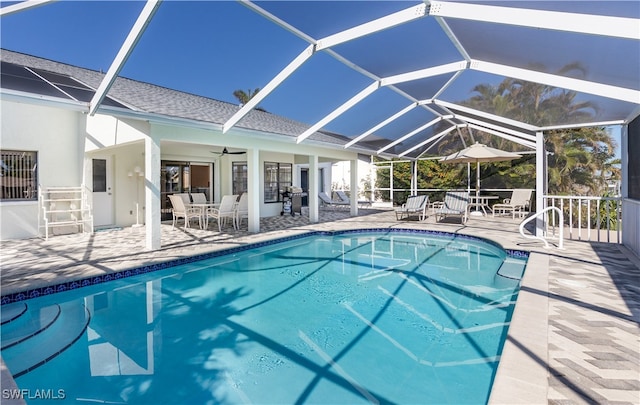 view of pool featuring glass enclosure, ceiling fan, and a patio area