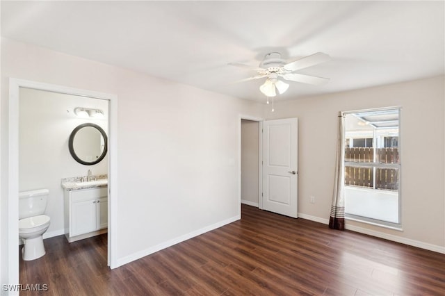 unfurnished room with a ceiling fan, a sink, dark wood finished floors, and baseboards