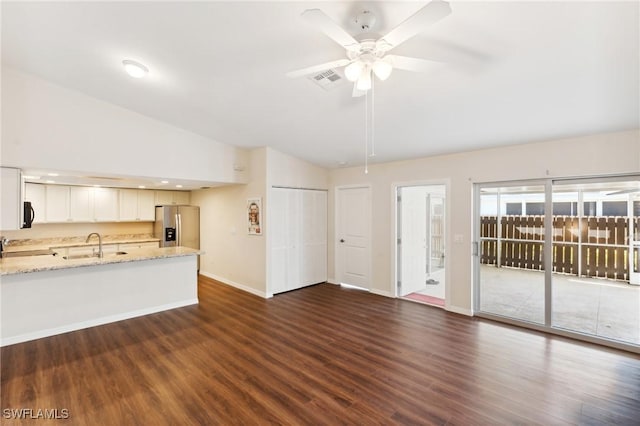 unfurnished living room featuring dark wood-type flooring, lofted ceiling, a sink, and ceiling fan