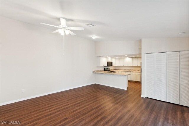 kitchen featuring visible vents, dark wood-type flooring, a peninsula, white cabinetry, and black microwave