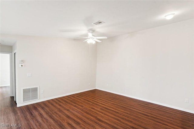 spare room with dark wood-style flooring, visible vents, and baseboards