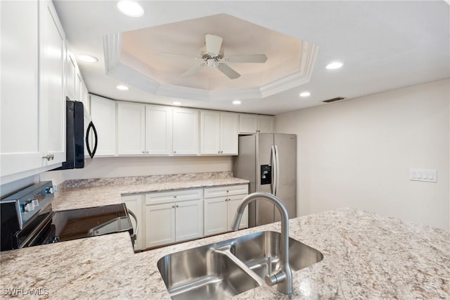 kitchen with a raised ceiling, visible vents, appliances with stainless steel finishes, white cabinets, and a sink