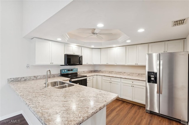 kitchen featuring a peninsula, appliances with stainless steel finishes, a sink, and white cabinetry