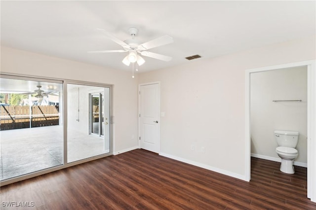 empty room with dark wood-style floors, baseboards, visible vents, and a ceiling fan