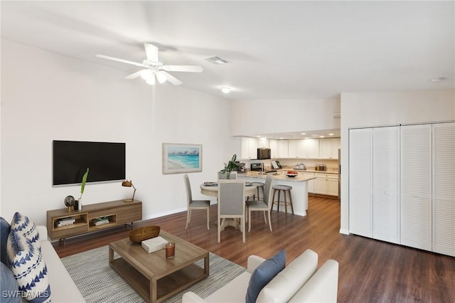 living area with lofted ceiling, ceiling fan, visible vents, and dark wood finished floors