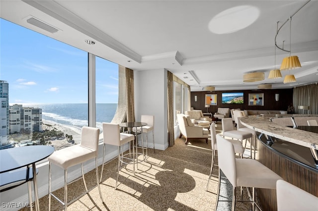 dining room with ornamental molding, a tray ceiling, light colored carpet, a view of the beach, and wood walls