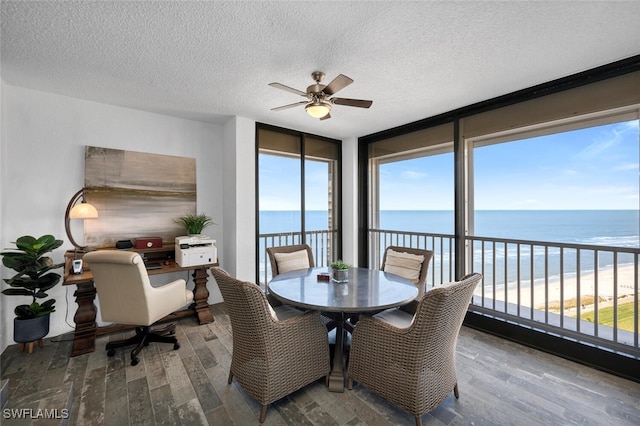 dining area featuring a water view, wood-type flooring, and a textured ceiling