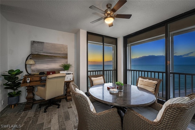 sunroom with ceiling fan and a water view