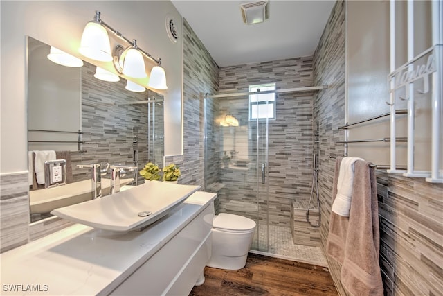 bathroom with walk in shower, tasteful backsplash, hardwood / wood-style floors, toilet, and tile walls