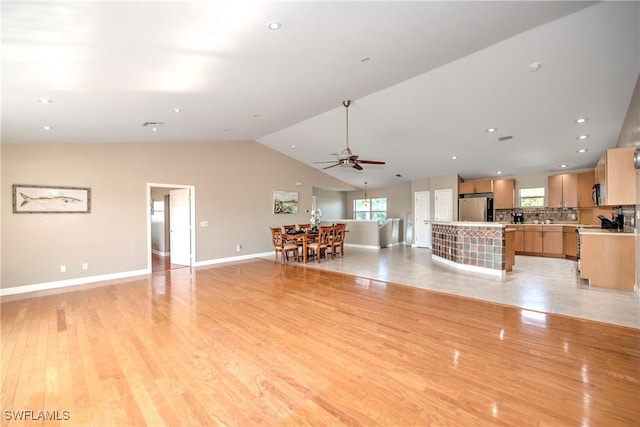 unfurnished living room featuring ceiling fan, lofted ceiling, and light wood-type flooring