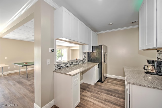 kitchen featuring stainless steel fridge, white cabinets, light wood-type flooring, and ornamental molding