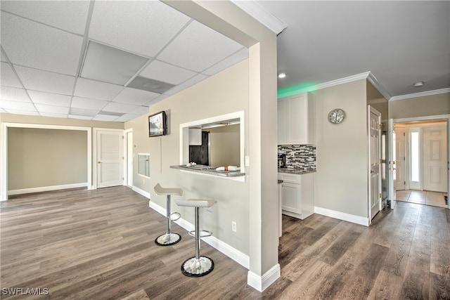 hall with dark hardwood / wood-style floors, a drop ceiling, and crown molding