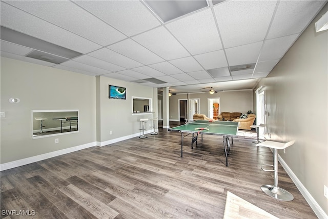 game room with ceiling fan, a drop ceiling, and wood-type flooring