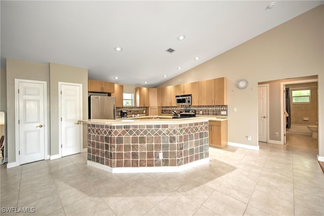 kitchen with appliances with stainless steel finishes, a kitchen island with sink, lofted ceiling, and light tile patterned flooring