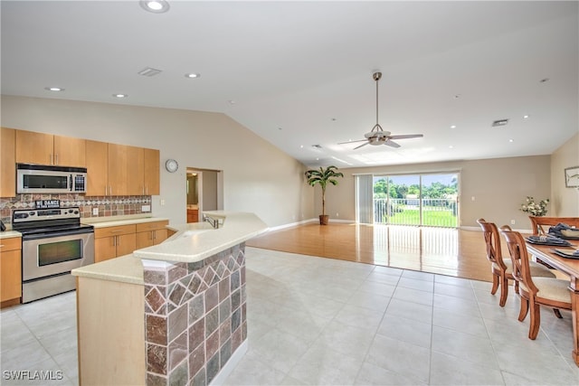 kitchen featuring appliances with stainless steel finishes, backsplash, ceiling fan, light hardwood / wood-style flooring, and lofted ceiling