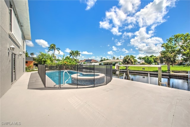 view of swimming pool with a patio area, a water view, and an in ground hot tub