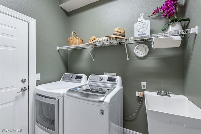 laundry room featuring laundry area, independent washer and dryer, a textured wall, and a sink