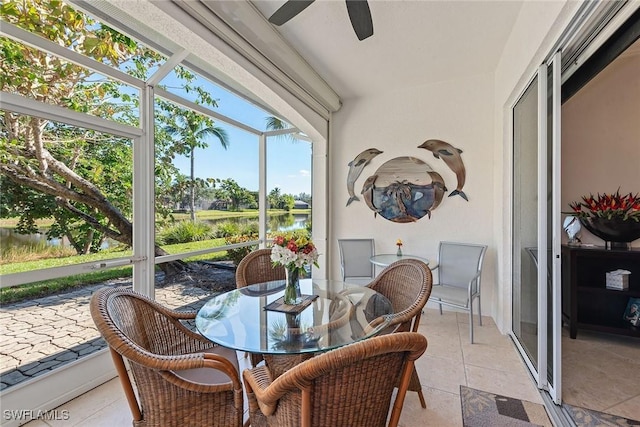 sunroom with ceiling fan and a water view