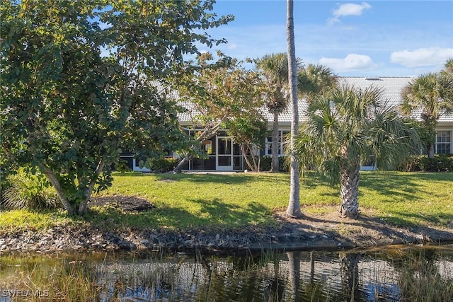 rear view of property featuring a lawn and a water view