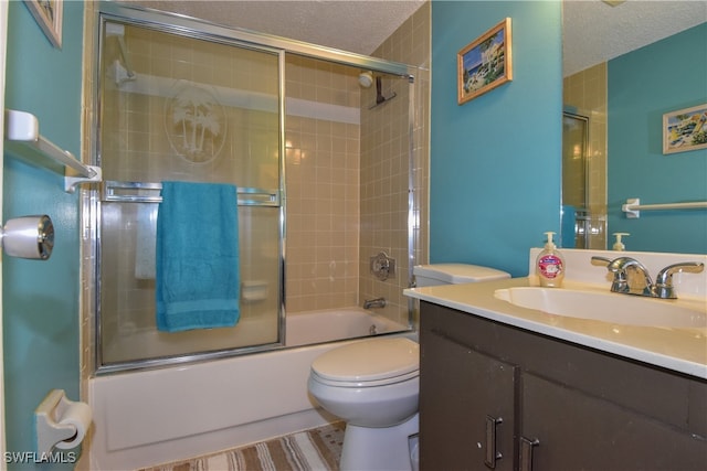 full bathroom featuring vanity, toilet, bath / shower combo with glass door, and a textured ceiling