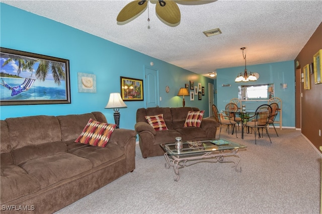 living room featuring ceiling fan with notable chandelier, carpet, and a textured ceiling