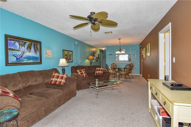 living room featuring carpet flooring, ceiling fan with notable chandelier, and a textured ceiling